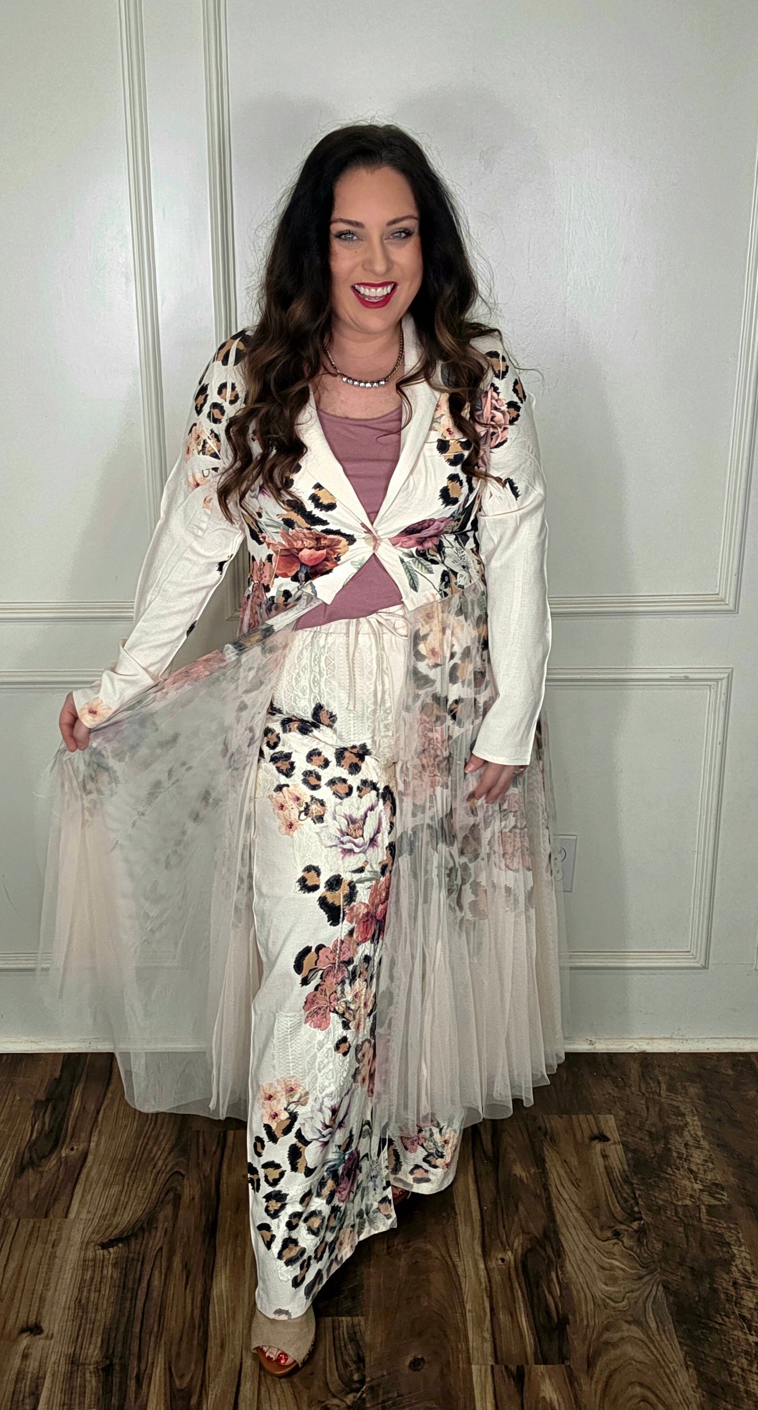 Woman wearing a floral and leopard print dress with a white cardigan indoors.