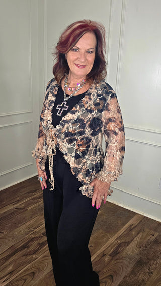 Woman wearing a floral top and black pants indoors.