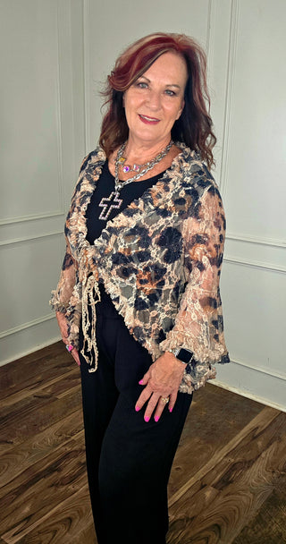 Woman wearing a floral shawl over a dark outfit indoors.