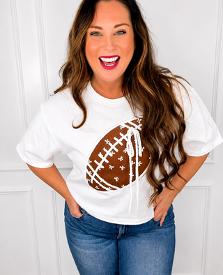 Woman wearing a white t-shirt with a brown football graphic design against a white background