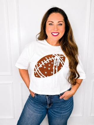 Woman wearing a white t-shirt with a brown football design against a white background