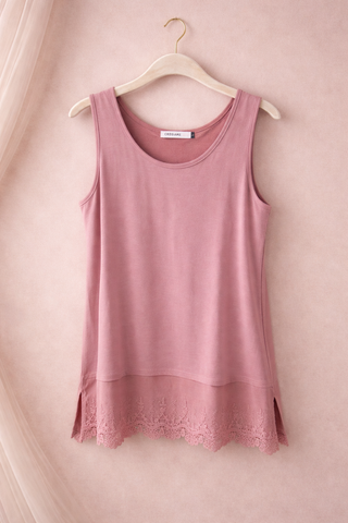 Pink tank top with lace hem on a hanger against a pink background