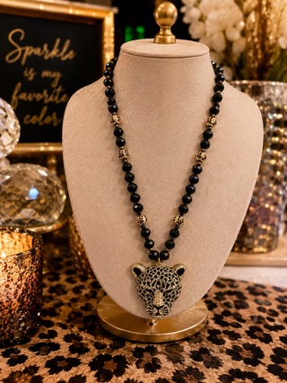 Necklace with leopard pendant on a mannequin bust against a decorative background