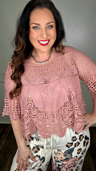 Woman wearing a pink crochet top with a neutral background